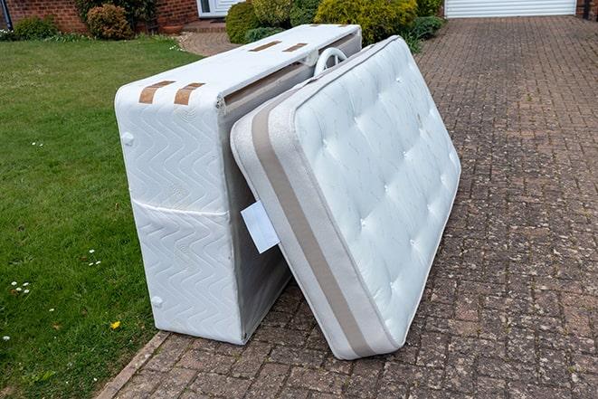 two people carrying mattress out of the house